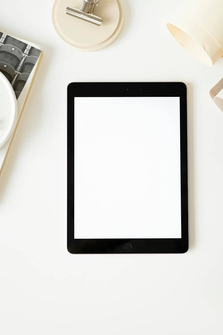 Top view of a minimalist workspace layout featuring a blank tablet screen for creative design purposes.